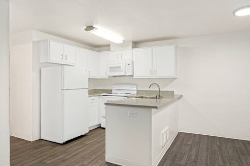 A white kitchen with a refrigerator, microwave, and cabinets.