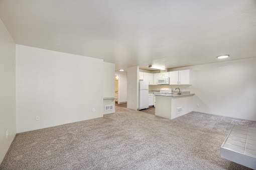 A spacious living area with a kitchen in the background.