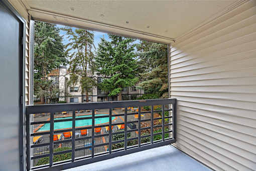 A balcony with a view of a pool and trees.