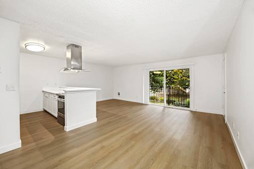 A white kitchen with wooden floors and a window.