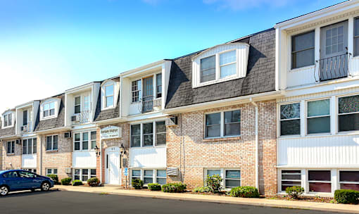 A blue car is parked in front of a row of townhouses.