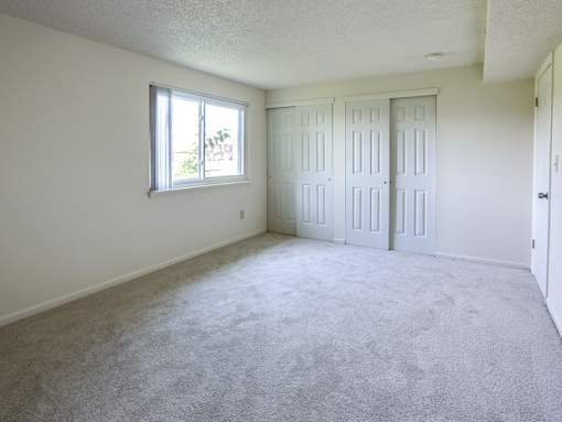an empty living room with two doors and a window