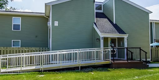 A green house with a white fence and a small porch.