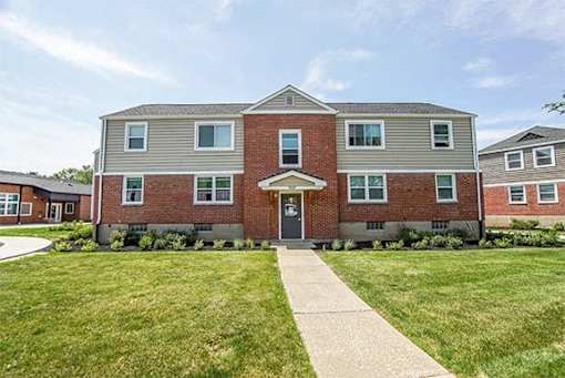 A brick building with a front yard and a walkway leading to the front door.
