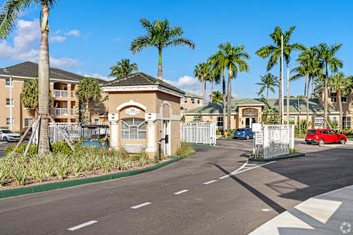 A street view of a residential area with palm trees and houses.