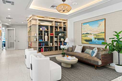 A living room with a bookshelf, a couch, and a painting on the wall.