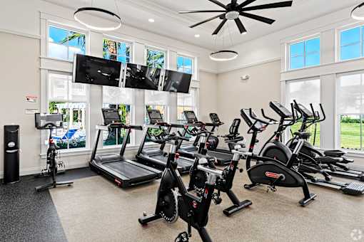 A spacious gym with treadmills, elliptical machines, and a television.