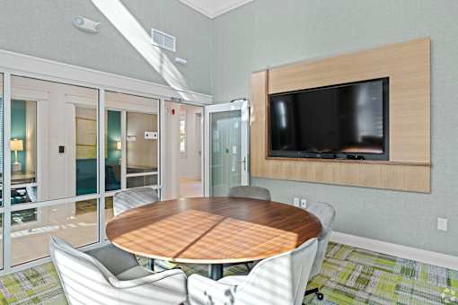 A conference room with a table, chairs, and a television.