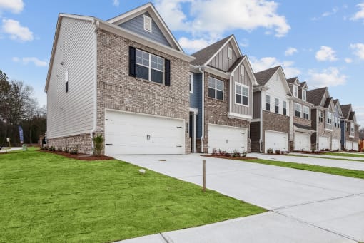 a row of houses with white garage doors and a green lawn