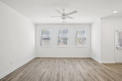 an empty living room with white walls and a ceiling fan