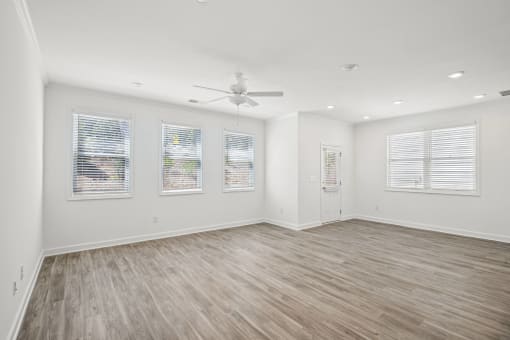 an empty living room with white walls and a ceiling fan
