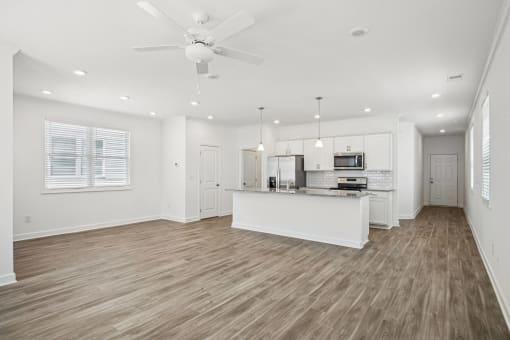 a living room with a kitchen and a ceiling fan