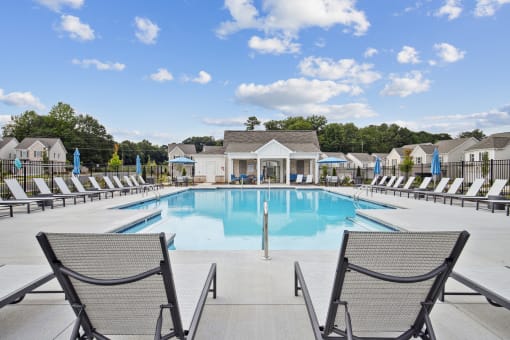 a swimming pool with chairs and a building in the background