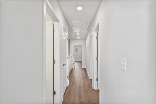 a hallway with white walls and white doors and a wood floor