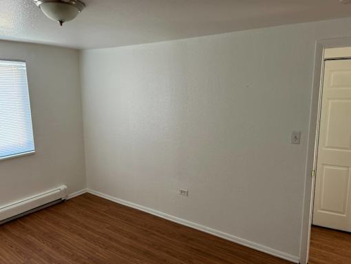 A room with a white wall and a wooden floor.