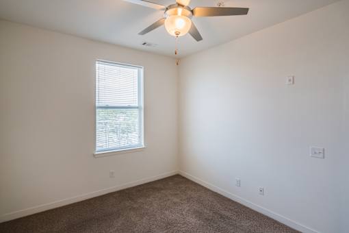 A room with a ceiling fan and a window.