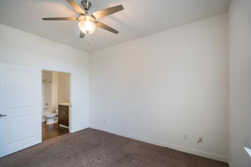 A room with a ceiling fan and carpeted floor.
