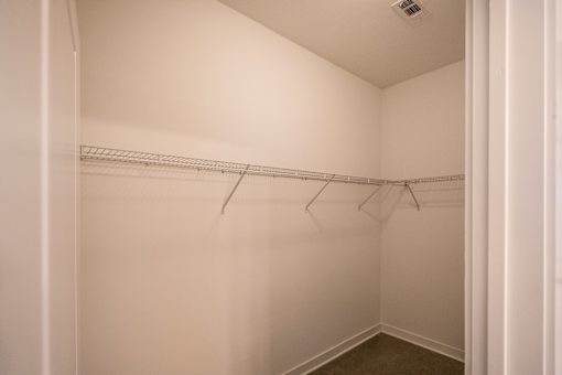 A white closet with a metal rack on the wall.