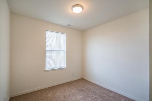 A room with a window and carpeted floor.