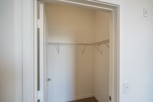 A white door is open to a room with a coat rack.