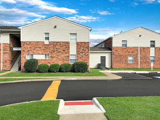 A street view of a residential area with apartment buildings and a parking lot.