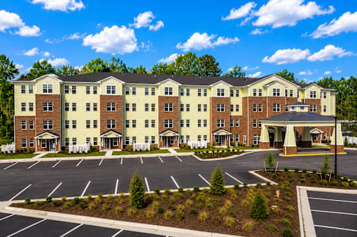 A large hotel with a parking lot in front.