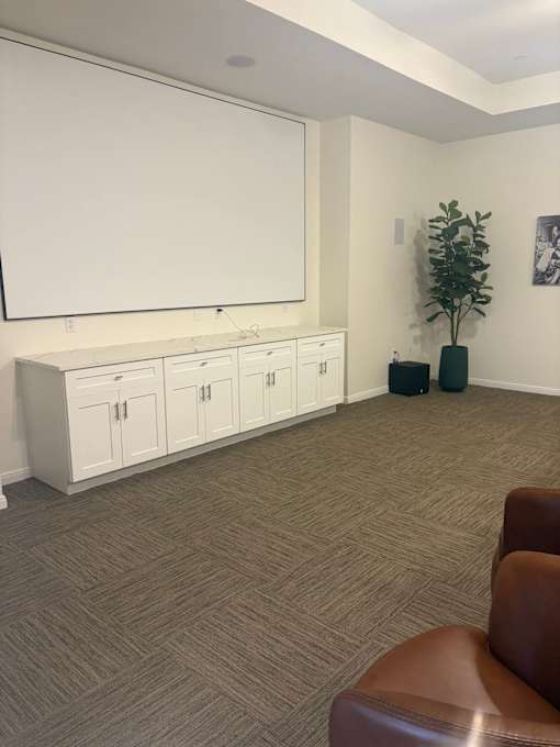 A room with a brown chair and a white cabinet with drawers.