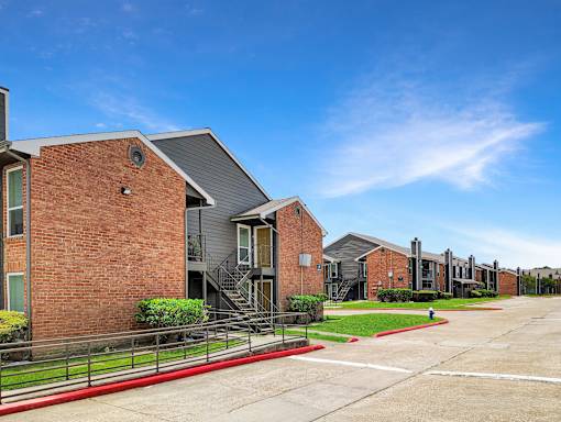 A row of modern brick apartment buildings with green lawns in front.