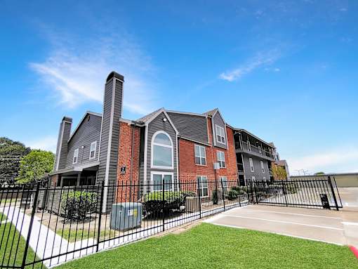 A large brick building with a black fence in front.