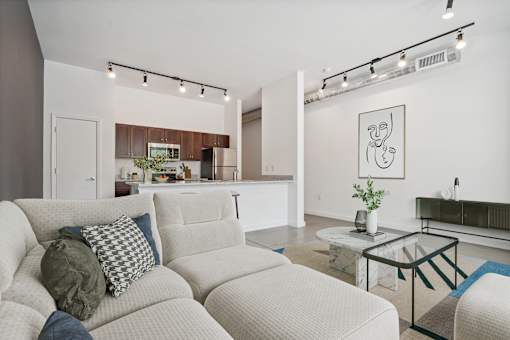 A living room with a white couch and a glass coffee table.