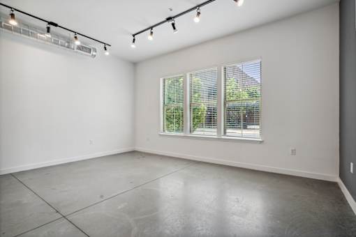A large empty room with a window and a ceiling fan.