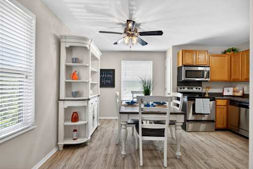 A kitchen with a white ceiling fan and wooden floors.