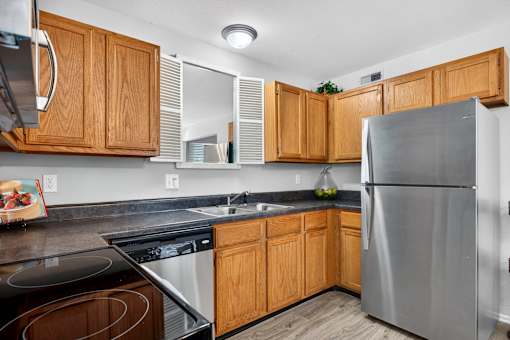 A kitchen with wooden cabinets and a stainless steel refrigerator.