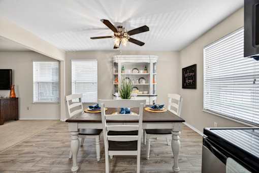A dining room with a table set for two and a ceiling fan.