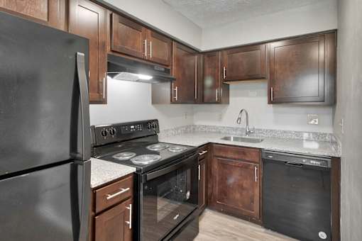 an empty kitchen with black appliances and wooden cabinets