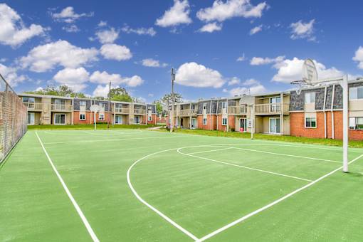 A tennis court is surrounded by apartment buildings.