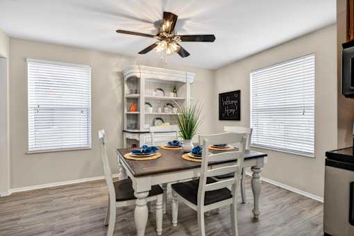 A dining room with a table set for two and a chalkboard on the wall.