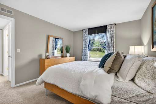 A bedroom with a large bed and a window with curtains.