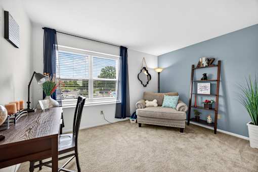 A room with a window, a chair, a table, a couch, and a potted plant.