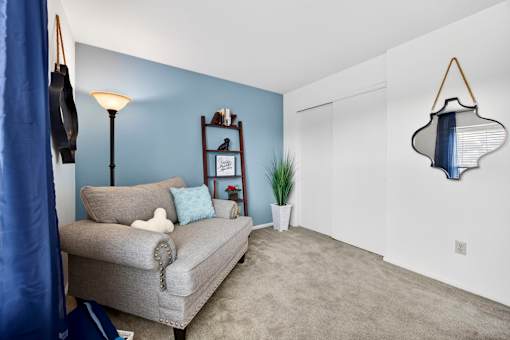 A grey couch with a white pillow and a white teddy bear on it.