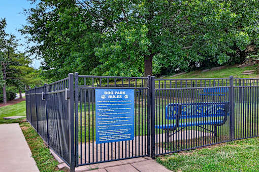 A sign for dog park rules is posted on a fence.