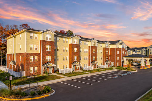 A large apartment complex with a parking lot in front.