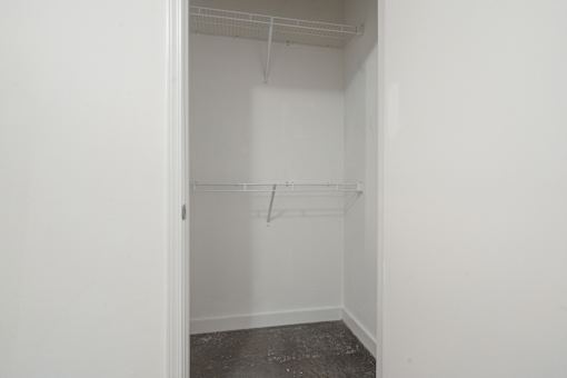 A white closet with a shelf and a door.