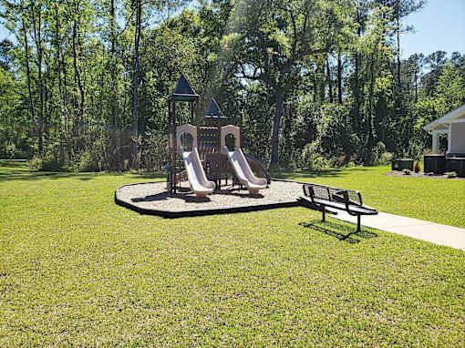 A playground with a slide and a bench in the foreground.