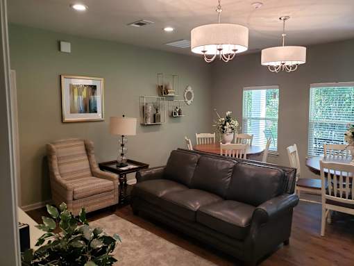 A living room with a brown leather couch, a striped armchair, and a small table with a lamp.