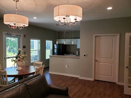 A brown leather couch sits in a living room with a dining table and chairs.