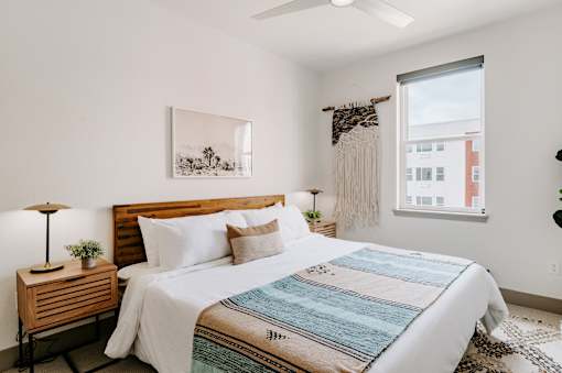 A bedroom with a large bed and a wooden nightstand.