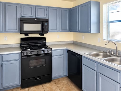 A kitchen with a black stove and blue cabinets.