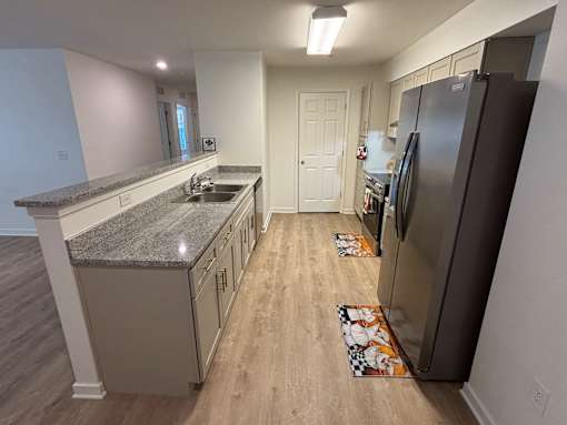 A kitchen with a granite counter top and a refrigerator.