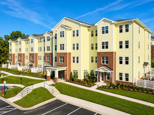 A large, multi-story apartment building with a parking lot in front.